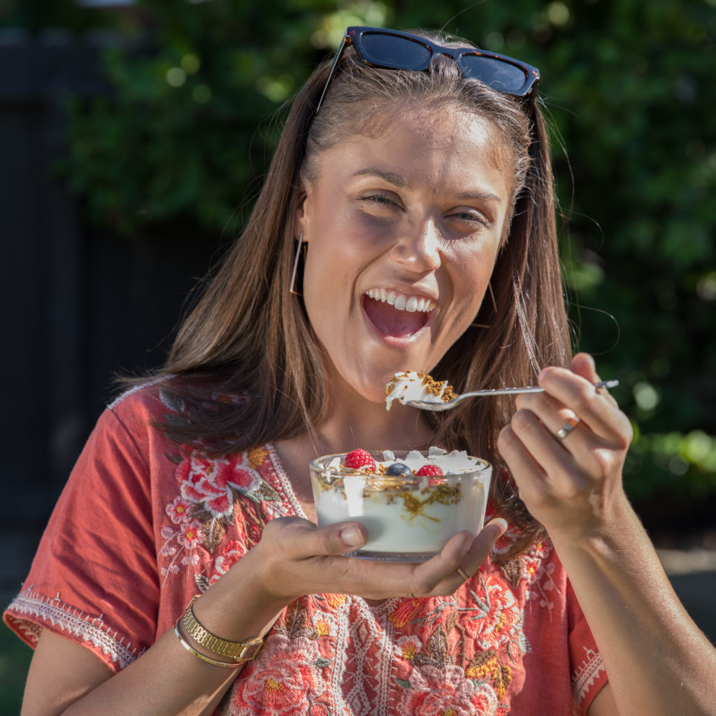 Smiling girl eating granola with yogurt and bee pollen, HummingBee Bee Products