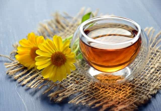 A beautiful open jar of honey and two flowers