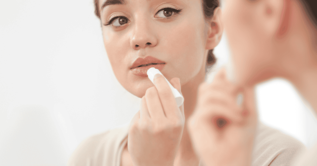 Girl applying a lip balm on her lips